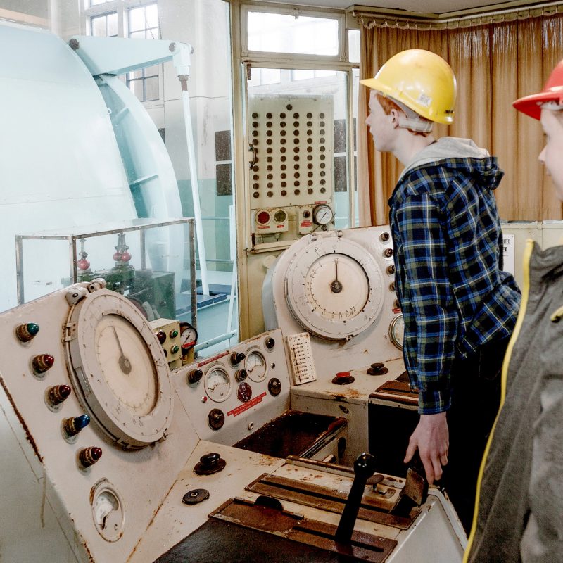 teenagers looking at mining machinery in compressor house at Geevor